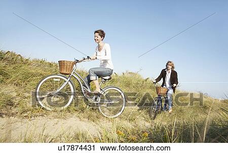 Couple cycling in field View Large Photo Image Stock Image - Couple cycling in field. Fotosearch