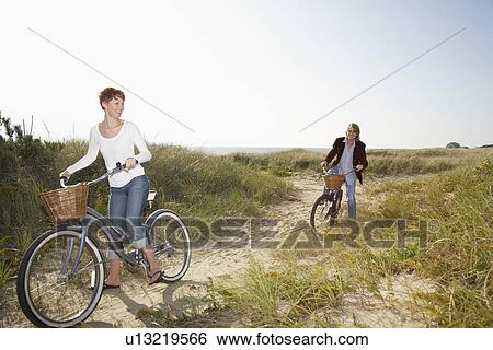 Couple cycling in field View Large Photo Image Stock Photograph - Couple cycling in field. Fotosearch