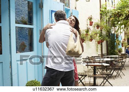 Stock Photo - Couple hugging outside café. Fotosearch
