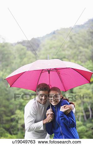 Couple hugging under umbrella View Large Photo Image Stock Image - Couple hugging under umbrella. Fotosearch