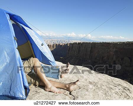 Stock Photo - Couple sleeping in tent by cliff, Moab, Utah, USA. Fotosearch