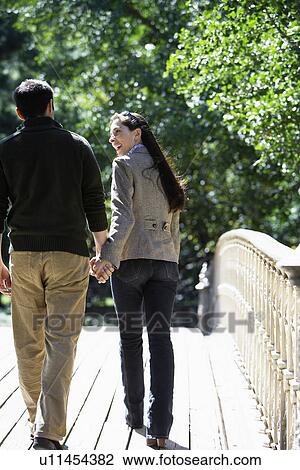 Couple walking on footbridge (rear view) View Large Photo Image Stock Image - Couple walking on footbridge (rear view). Fotosearch