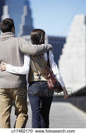 Couple walking with arms around each other (rear view) View Large Photo Image Stock Image - Couple walking with arms around each other (rear view). Fotosearch