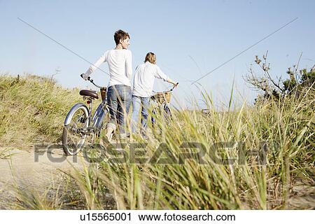 Couple with bicycles walking on path View Large Photo Image Stock Image - Couple with bicycles walking on path. Fotosearch