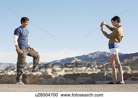 Woman photographing man by stone wall in desert, Death Valley, California, USA View Large Photo Image Stock Image - Woman photographing man by stone wall in desert, Death Valley, California, USA. Fotosearch
