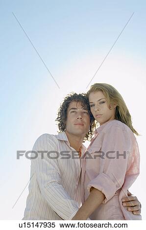 Young couple against clear sky (portrait, low angle view) View Large Photo Image Stock Photography - Young couple against clear sky (portrait, low angle view). Fotosearch