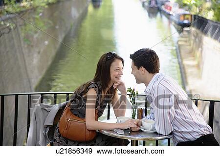 Stock Photo - Young couple holding hands at café. Fotosearch
