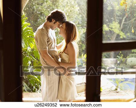 Stock Image - Young couple hugging on doorway. Fotosearch