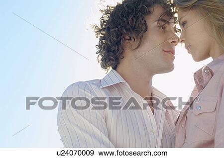 Young couple looking at each other (low angle view) View Large Photo Image Stock Photo - Young couple looking at each other (low angle view). Fotosearch