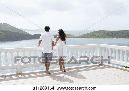 Young couple looking at ocean on balcony, St. John, US Virgin Islands, USA View Large Photo Image Picture - Young couple looking at ocean on balcony, St. John, US Virgin Islands, USA. Fotosearch