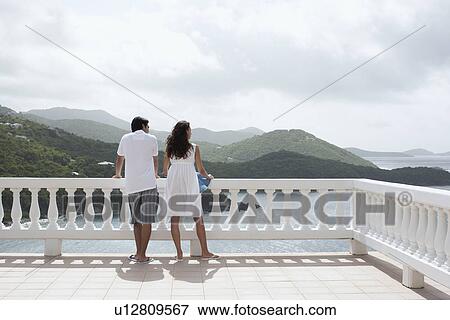 Young couple looking at ocean on balcony, St. John, US Virgin Islands, USA View Large Photo Image Stock Photo - Young couple looking at ocean on balcony, St. John, US Virgin Islands, USA. Fotosearch