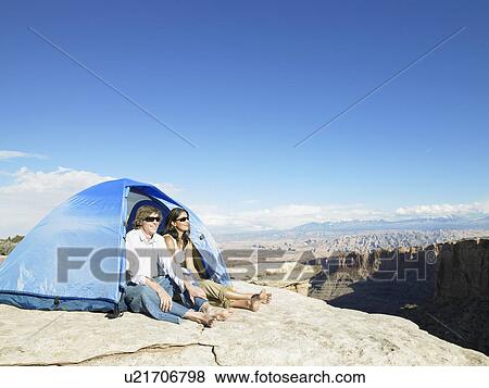 Stock Photo - Young couple sitting in tent by cliff, Moab, Utah, USA. Fotosearch