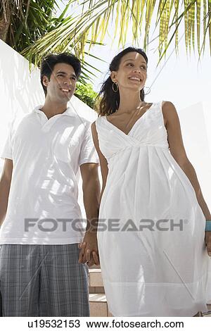 Stock Image - Young couple walking down steps with luggage. Fotosearch