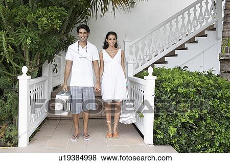 Stock Photo - Young couple with luggage standing at resort. Fotosearch