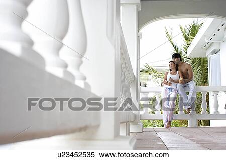 Young couple with mugs standing on terrace (low angle view) View Large Photo Image Stock Photography - Young couple with mugs standing on terrace (low angle view). Fotosearch