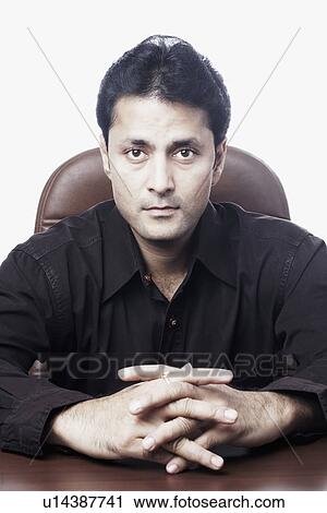 Stock Image - Portrait of a businessman sitting with his hands clasped. Fotosearch