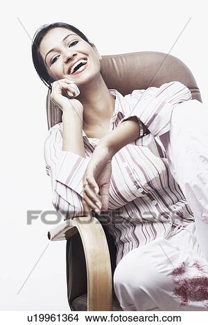 Picture - Portrait of a businesswoman sitting on a chair talking on a mobile phone. Fotosearch