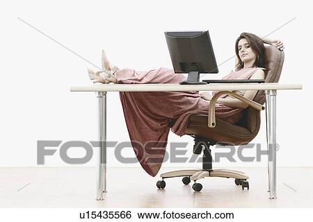 Stock Photograph - Portrait of a businesswoman with her feet up on the table. Fotosearch