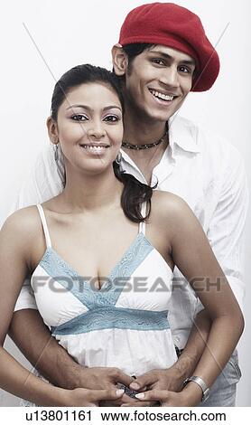 Stock Image - Portrait of a young man embracing a young woman from behind. Fotosearch