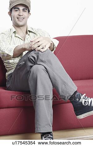 Portrait of a young man sitting on a couch View Large Photo Image Picture - Portrait of a young man sitting on a couch. Fotosearch