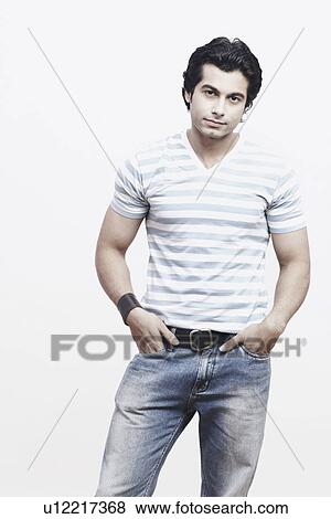 Portrait of a young man standing with his hands in his pockets View Large Photo Image Stock Photo - Portrait of a young man standing with his hands in his pockets. Fotosearch