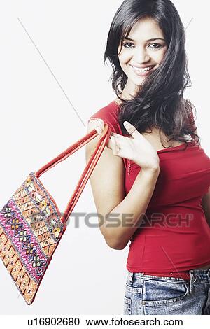 Stock Image - Portrait of a young woman holding a hand bag. Fotosearch