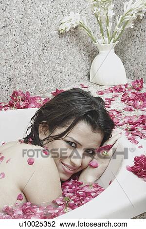 Stock Image - Portrait of a young woman lying in a bathtub. Fotosearch