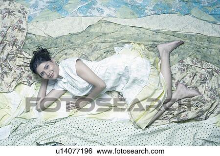 Portrait of a young woman lying on fabric View Large Photo Image Stock Photograph - Portrait of a young woman lying on fabric. Fotosearch