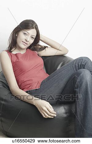 Stock Photo - Portrait of a young woman sitting on a bean bag. Fotosearch