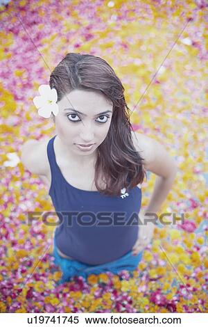 Stock Photography - Portrait of a young woman standing in a swimming pool filled with flower petals. Fotosearch