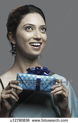 Stock Photograph - Close-up of a young woman holding a gift. Fotosearch