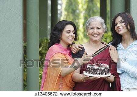 Portrait of a mature woman holding a cake with a young woman and a mid adult woman standing beside her View Large Photo Image Stock Image - Portrait of a mature woman holding a cake with a young woman and a mid adult woman standing beside her. Fotosearch