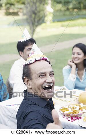 Stock Photo - Portrait of a senior man sitting at a table smiling. Fotosearch