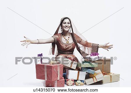 Portrait of a young woman smiling with a stack of gifts lying in front of her View Large Photo Image Stock Image - Portrait of a young woman smiling with a stack of gifts lying in front of her. Fotosearch