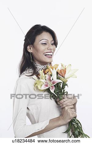 Side profile of a young woman holding a bunch of flowers View Large Photo Image Picture - Side profile of a young woman holding a bunch of flowers. Fotosearch