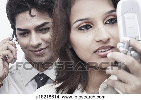 Picture - Close-up of a businessman and a businesswoman using mobile phones. Fotosearch
