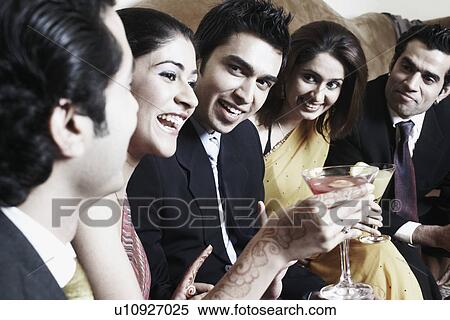 Stock Photography - Close-up of three young men and two young women holding martini glasses. Fotosearch