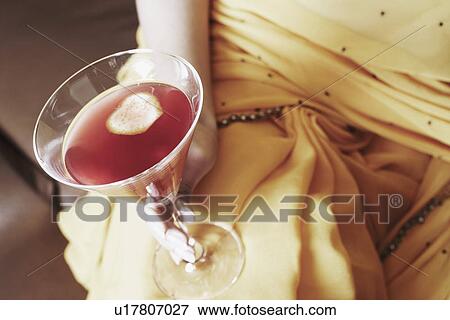 Mid section view of a young woman holding a martini glass View Large Photo Image Stock Photo - Mid section view of a young woman holding a martini glass. Fotosearch