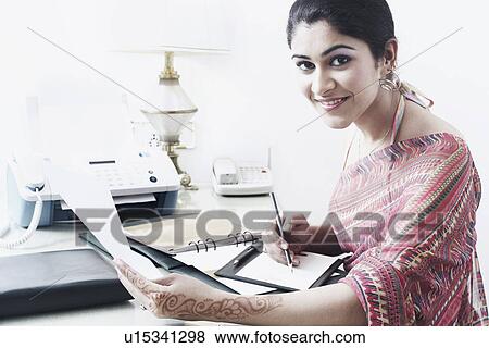 Stock Photo - Portrait of a young woman holding a pencil and paper. Fotosearch
