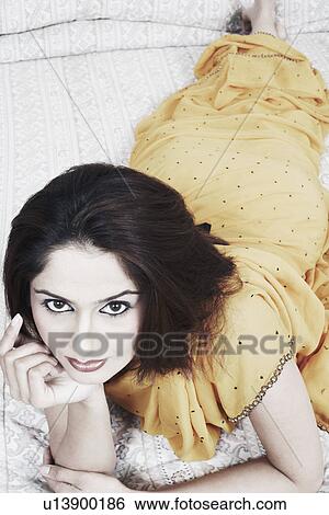 Portrait of a young woman lying on the bed View Large Photo Image Stock Photograph - Portrait of a young woman lying on the bed. Fotosearch