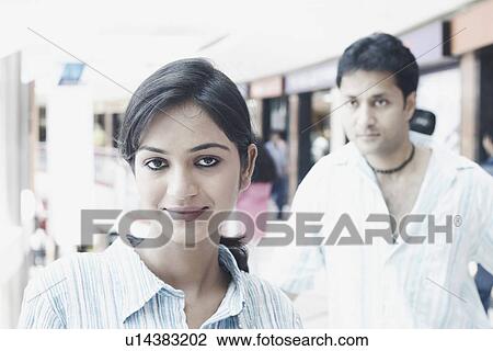 Stock Image - Portrait of a young woman with a young man standing behind her. Fotosearch