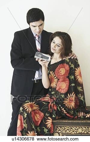 Young couple looking at a mobile phone View Large Photo Image Stock Photo - Young couple looking at a mobile phone. Fotosearch