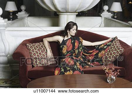 Young woman sitting on a couch View Large Photo Image Picture - Young woman sitting on a couch. Fotosearch