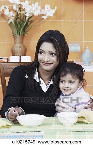 Stock Photo - Close-up of a mother with her daughter at the dining table. Fotosearch