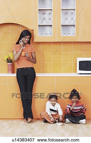 Mother talking on a mobile phone with her daughters sitting on the floor View Large Photo Image Stock Photo - Mother talking on a mobile phone with her daughters sitting on the floor. Fotosearch