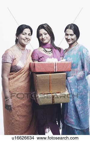 Portrait of a young woman holding gifts standing with her mother and her sister View Large Photo Image Picture - Portrait of a young woman holding gifts standing with her mother and her sister. Fotosearch