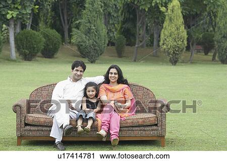 Portrait of parents sitting on a couch outdoors with their daughter View Large Photo Image Stock Image - Portrait of parents sitting on a couch outdoors with their daughter. Fotosearch
