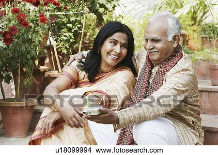 Picture - Close-up of a mature woman looking at a mature man holding a digital camera. Fotosearch