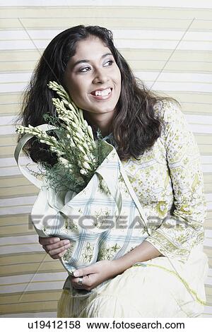 Stock Photo - Close-up of a young woman holding a bag of flowers. Fotosearch