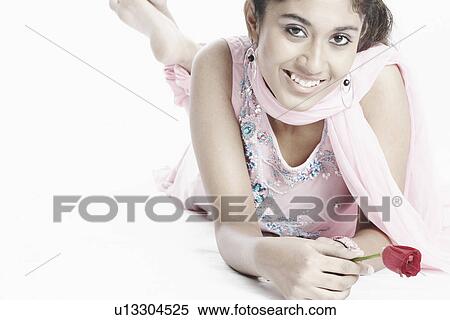 Stock Photography - High angle view of a young woman lying down holding a flower. Fotosearch